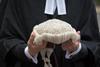 An anonymous barrister holds their wig in front of them