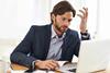 Man looks at laptop in confusion