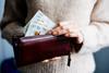 A woman takes £10 notes out of a purse