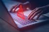 Cyber security concept image. Red warning sign hovers above laptop keyboard