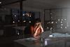 A woman sits at her office desk late at night with her head in her hands