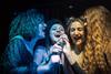 Four women share a microphone during karaoke