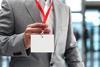 Anonymous man wearing a suit holds up his ID card