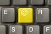 A yellow key on a computer keyboard shows a smiley face