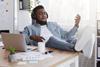 Man wearing headphones reclines in chair playing air guitar with eyes closed