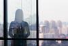 A silhouette of a woman against the backdrop of a window overlooking a city skyline