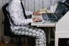 Man on laptop at desk in pyjamas