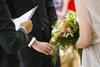 An officiant conducts a wedding ceremony with a bride and groom