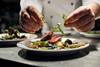 A chef places the finishing touches to a plate of food in a restaurant kitchen