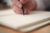 A close up of a man's hand holding a pen to paper