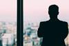 Male office worker looks out of a window