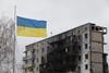 A Ukrainian flag flies in front of an apartment building that was damaged as a result of shelling by Russian troops in Borodianka