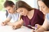 A student checks her phone during school exam