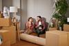 A couple sit on the floor of their new home surrounded by boxes