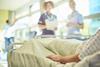 A patient lies in a hospital bed while nurses stand nearby