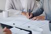 Clients sign a document with their solicitor