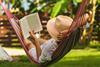 Woman lounges in hammock while reading on holiday