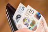 A £5 and £10 note being pulled out of a wallet
