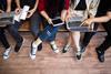 A group of anonymous young people gather around laptops and tablets