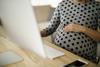 A pregnant woman rests her hand on her bump as she works on her computer
