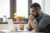 Young man thinking while sat at computer