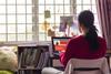 Teenage girl sat at bedroom desk working on laptop