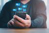 A man looks at his phone with various social media graphics appearing above the screen