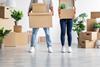 An anonymous young couple carry boxes as they move in together