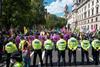 A line of police officers stand in front of a crowd of protesters