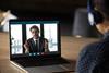 Laptop screen shows businessman talking to woman via Skype