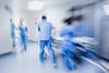 Blurred figures of hospital staff in scrubs rushing patient to surgery