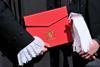 Newly appointed legal member of the King's Counsel (KC) poses with letters of patent and white gloves on 'Silks Day'
