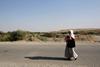 A woman from the minority Yazidi sect, fleeing the violence in the Iraqi town of Sinjar, walks to a refugee camp