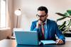 A man wearing a suit looks at his laptop as he works from home