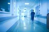 A blurred image of a doctor walking down a hospital corridor