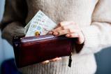 A woman takes £10 notes out of a purse