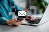 Red exclamation mark over an email symbol, with a person working on a laptop in the background