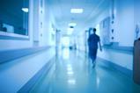 A blurred image of a doctor walking down a hospital corridor