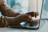 A man types on a laptop keyboard