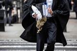 A barrister holds his wig on his way to court