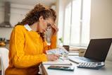 A young woman looks at bills at home