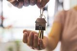 A woman holds out her hand to receive a set of keys to a new house