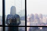 A silhouette of a woman against the backdrop of a window overlooking a city skyline