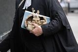 A barrister holds his wig on his way to court