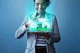 A woman looks down at a virtual house projected from the screen of a tablet