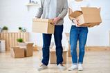 An anonymous couple carry moving boxes