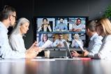 A group of four colleagues sit round a table while listening to clients on a virtual call