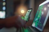 Hacker holds phone showing coding