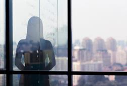 A silhouette of a woman against the backdrop of a window overlooking a city skyline