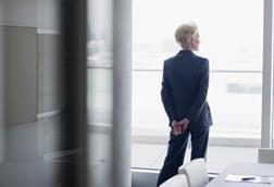 An older businesswoman looks out of an office window